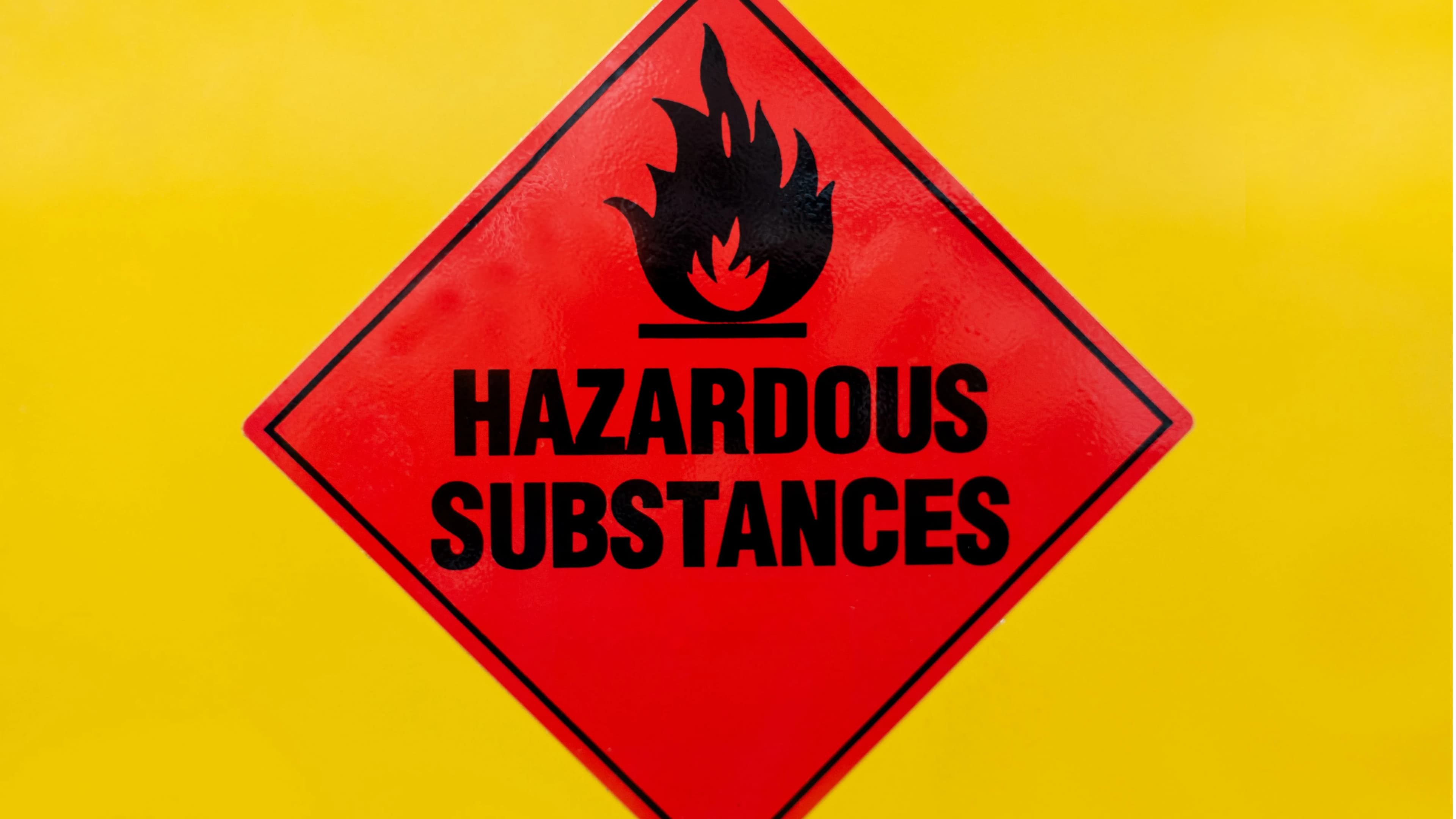 An image of a hazardous waste, yellow background with a red triangle and hazardous substance written in the triangle